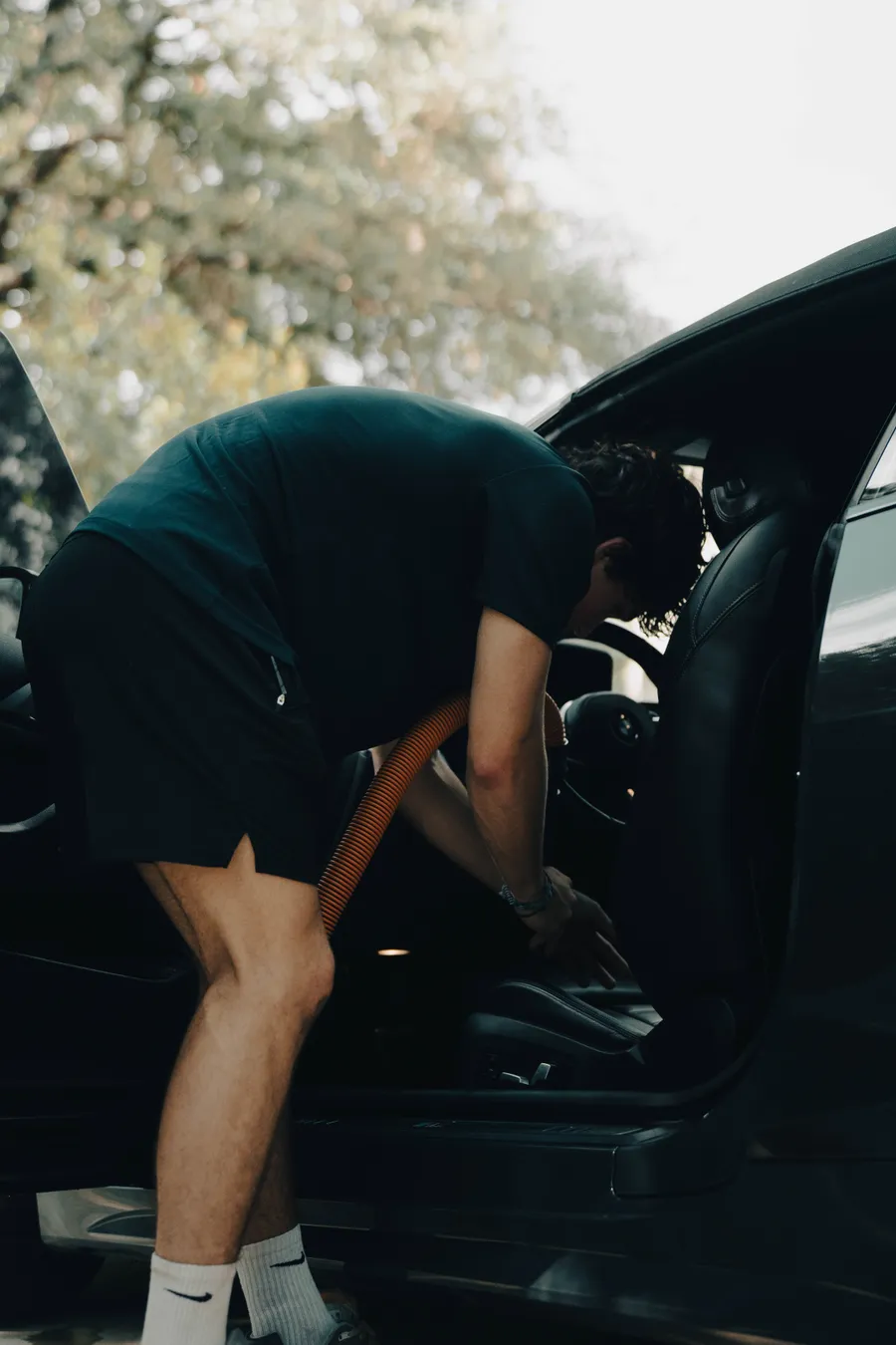 Detailer extracting a car interior with a wet/dry vacuum hose